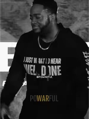 A black and white image features a man, viewed from the chest up, in a black hoodie. The hoodie has text that reads 'I JUST WANT TO HEAR WELL DONE' in bold white letters. Below that, the word '@POWERFUL' is displayed. The man has a short beard, dark hair, and a silver chain around his neck. The background is blurred. The bottom of the image displays the word 'POWERFUL' in a blocky sans-serif font.