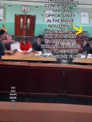 The image captures a scene from what appears to be a courtroom or an office boardroom, featuring blurred figures seated around a long table. Overlaid on the scene is overlaid text in a white font, alongside a yellow arrow pointing to an area that the text is referring to.