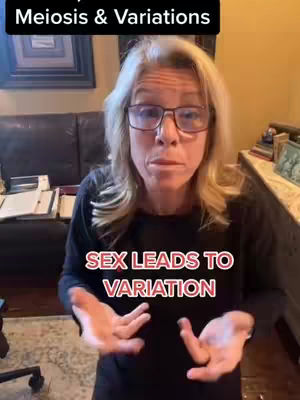 A middle-aged woman with blonde hair and glasses is speaking to the camera in front of a dark leather sofa and a wooden cabinet. Text overlays appear on the image, with one at the top and another at the bottom.