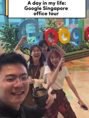A selfie-style photo taken in an office setting. The main subject is a man in the foreground, holding a black cup, seemingly smiling. Behind him, there are three women smiling, with the Google logo in the background. The text overlay mentions Google Singapore.