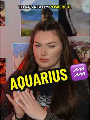 A woman with long brown hair is centered in the frame. She is gazing towards the camera with a neutral expression, her hands clasped in front of her. The background has various pictures and posters. Overlayed on the image is the word 'AQUARIUS' in yellow capital letters with a black outline. Beside it is a purple square with the Aquarius symbol. Above, a yellow banner reads 'THAT'S REALLY POWERFUL'.