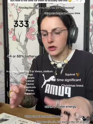 A woman with dark hair, glasses, and headphones is centered in the frame, engaged in a discussion. The background includes a decorative screen with floral patterns. Additional text and graphics overlay the image.