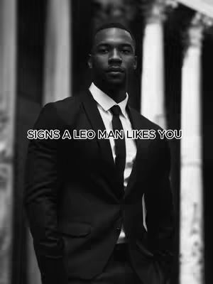 A black and white photo of a man in a suit looking directly at the camera. Text overlay in white at the bottom says 'SIGNS A LEO MAN LIKES YOU'. The background is blurred, suggesting an outdoor setting with architectural columns.