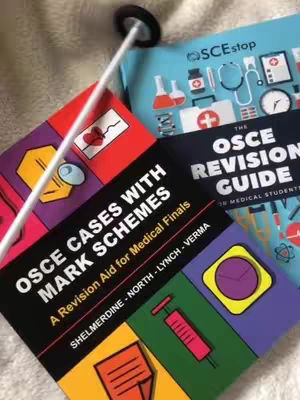 The cover image shows a close-up of medical textbooks and a neurological reflex hammer. The books are mostly in focus. "OSCE Cases with Mark Schemes" is clearly visible. The books are arranged with a tilt, with other book titles and design elements visible, along with medical-related icons. The background is slightly blurry.