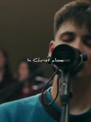The cover image shows a close-up of a man singing into a microphone. The main subject is wearing a blue shirt. There is text overlayed. Soft lighting and a blurred background suggest a performance or rehearsal setting.
