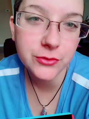 A medium close-up focuses on a person's face, with a cropped hairstyle, glasses, and a blue top, featuring a pendant necklace and red lipstick.