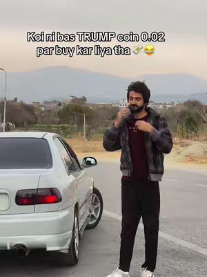 A man stands next to a white car on a road, an overlay on the image says that he bought a TRUMP coin.