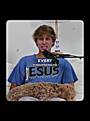 A young man with curly blonde hair sits on a white couch, smiling at the camera while holding a microphone. A brown fluffy dog is lying on his lap. The man is wearing a blue shirt with the white text "JESUS" and the text: "TO HEAVEN" in black. A text overlay at the top shows the words "EVERY @JESUSISKING.IVA". Behind him, there's a bottle, and a microphone stand. The background is a solid light color.