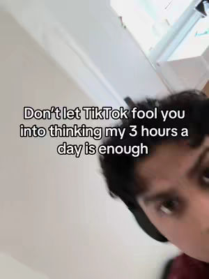 A selfie-style video cover image showing a person with dark hair and a red shirt. The person's face is near the bottom right, and the background is a white wall and ceiling. Text overlayed on the image says, "Don't let TikTok fool you into thinking my 3 hours a day is enough."