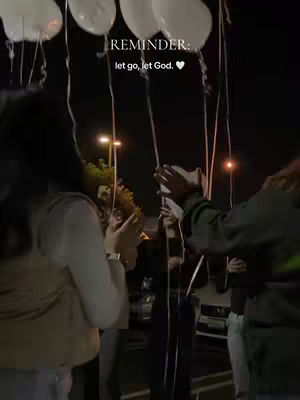 A night scene with several people holding up white balloons. Text is overlaid on top.