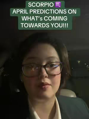 A selfie-style video featuring a woman with glasses seated in a vehicle. She's looking at the camera with a neutral expression. Above her head, a green rectangle displays white text about Scorpio predictions for April.