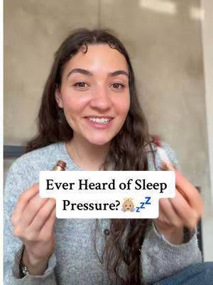 A woman with long, wavy brown hair smiles at the camera while holding what appears to be makeup applicators. A white rectangular text overlay reads "Ever Heard of Sleep Pressure?" and includes a baby emoji and ZZZ symbols.
