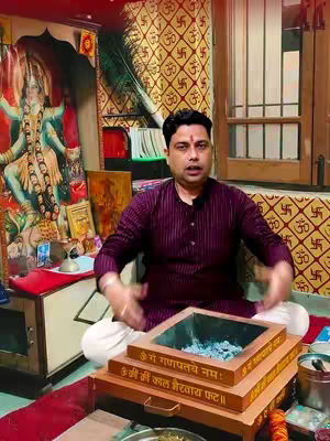 The cover image displays a man sitting cross-legged in front of a small altar. He's wearing a dark purple shirt, with texts in a square wooden box placed in front of him. The background features a framed deity image, fabric with repeating symbols, a window and other objects that give the impression of a traditional setting. The lighting is warm.