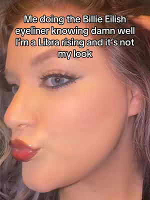 The cover image shows a close-up of a person, with the face filling most of the frame. The person has visible makeup, including dark eyeliner, glossy lips, and blush. The lighting is soft, and the background is out of focus. The person is angled towards the left, with their expression slightly puckered, as if they are blowing a kiss.