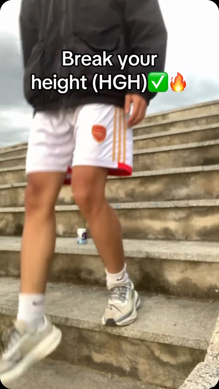 The image shows a person walking up a set of concrete stairs, with the legs and lower torso visible. The person is wearing white shorts with gold stripes and red trim, white socks, and gray and white sneakers.  Text overlaying the image reads "Break your height (HGH) ✓🔥".
