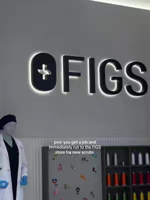 The cover image shows the word "FIGS" in large, bold, black letters against a plain white background. The letters are illuminated with a white light around their edges, giving them a glowing effect. The letter "O" features a plus sign within it, and the text "pov: you get a job and immediately run to the FIGS store for new scrubs" is written in the image hook.