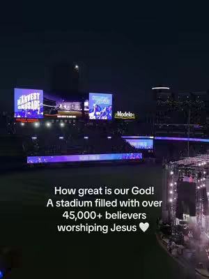 A nighttime stadium scene with large screens displaying 'Harvest Crusade'. Overlaid text describes the event, with stage lights and a crowd visible.