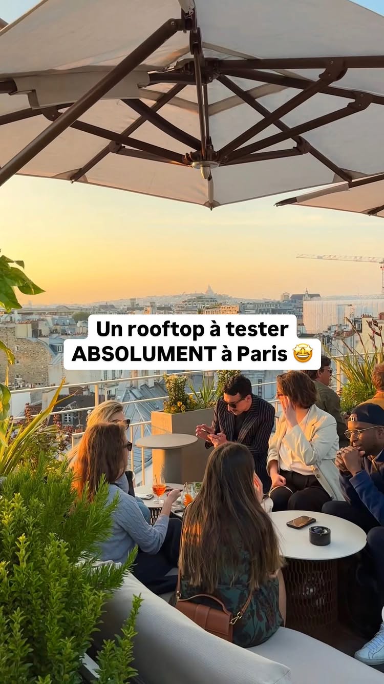 The cover image shows a group of people sitting on a rooftop, enjoying drinks and conversation. The background features a panoramic view of the Parisian skyline at sunset, with notable landmarks barely visible. An umbrella provides shade, and green plants adorn the edges of the rooftop. Text overlayed on the image promotes the rooftop as 'Un rooftop à tester ABSOLUMENT à Paris'.