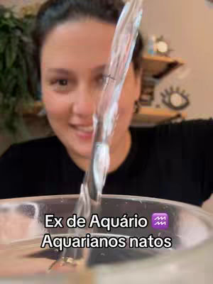 A woman is smiling and looking at the camera. Water is being poured from above, partially obscuring her face. Text overlays at the bottom read, "Ex de Aquário" and "Aquarianos natos."