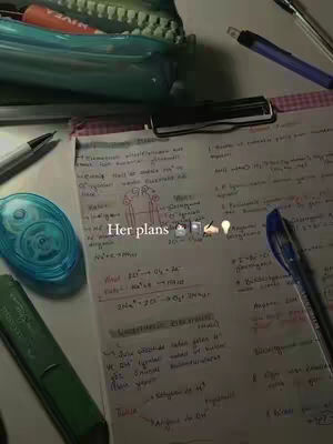 A desk with study supplies and notes. Lying on the desk is a notepad with a pen, a pencil case, a green highlighter, a tape roller, and some other pens.