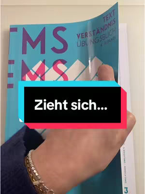 The cover image shows a person holding a book at an angle, with the book's cover partially peeled back. The book is mostly teal, with large purple letters. The hand holding the book is in focus, and there is a text overlay with the words 'Zieht sich...' in a black rectangle.