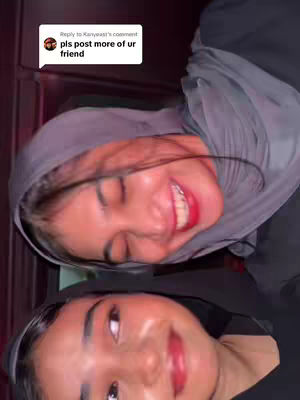 The image shows two young women in a selfie-style shot. They are positioned closely together, with their faces angled towards the camera. The women have smooth skin and red lipstick. One is wearing a gray headscarf. A comment box is visible in the upper left corner.