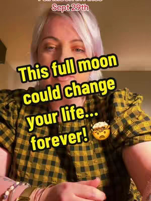 A woman with pink-tinged blonde hair is centered in the frame. She wears a plaid shirt with a yellow and black checkered pattern, and her arms are in view, with several bracelets and a watch on her wrist. A text overlay dominates the image, written in a yellow outlined font, and a tiny graphic of a stressed emoji is at the bottom. The background is blurred, with warm lighting, suggesting an indoor setting.