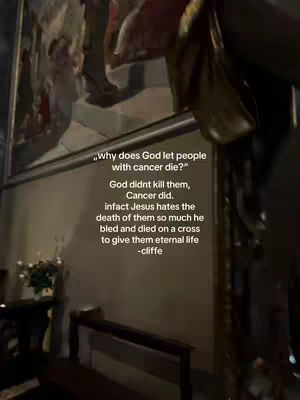 A vertical image captured in a dimly lit room. The scene is dominated by a large, detailed painting, likely a religious artwork, with figures and scenes painted in various colors. In the foreground, there's a textured surface along what appears to be a wall or a partition. The lighting is dim and warm, creating shadows and highlighting the textures of the surfaces. Overlay text provides a quote about cancer and God, along the right side of the image.