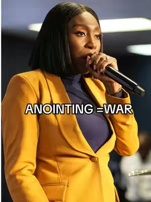 The cover image features a woman holding a microphone and speaking. She is wearing a mustard yellow blazer over a navy blue top. Text is added at the bottom, reading: "ANOINTING = WAR"
