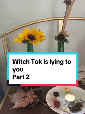 The cover image is a vertical video screenshot. The background has a light wall partially visible on the top left corner. On a dark wooden table, there are decorations, including a yellow sunflower in a green bottle, a dried flower arrangement in a green bottle to the right of the sunflower, and a scattering of various items. These items include a dried leaf, a small white plate with several items on top, and some crystals. Overlayed on the image is a light blue and white rectangle containing white text.