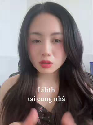 A woman with long, dark hair and red lipstick looks directly at the camera. Text overlayed on the image says "Lilith tại cung nhà" in Vietnamese.