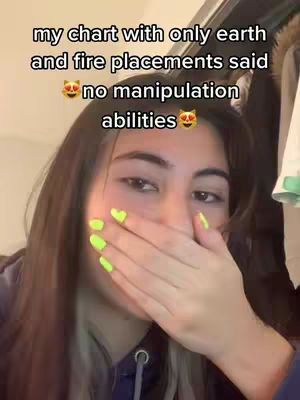 A selfie-style video cover image. A young person with long brown hair partially obscures their face with their left hand, which has lime green nail polish decorated with small yellow heart shapes on a few nails. The background seems to be partially visible, with items like a clothing rack. Text overlayed on the image that discusses astrological birth chart aspects and potential manipulation tendencies, accompanied by kawaii cat face emojis.