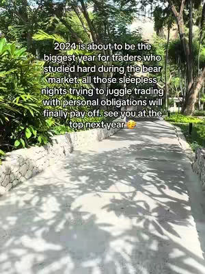 A paved path winds through a lush, green environment, flanked by low stone walls. Overhead, dense foliage filters the sunlight, creating dappled shadows on the path. Text is overlaid on the image.