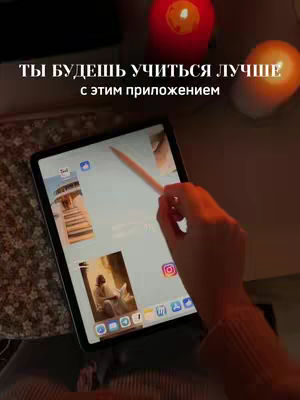 A person's hand holding a digital pen over an iPad that displays the app Flexcil. The frame includes candles and a dark background.