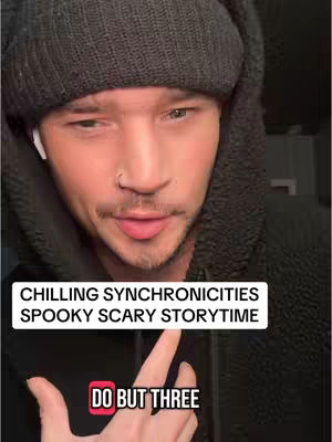 The cover image is a close-up shot of a man. He is wearing a black beanie and a dark hoodie, framing his face. The man has light skin, a subtle smile, a nose ring, and a shadow of a beard. He is wearing an earbud in his left ear. The background is blurry, rendering the focus on the man. Overlaid on the image are two text boxes: the first reads 'CHILLING SYNCHRONICITIES SPOOKY SCARY STORYTIME' and the second 'DO BUT THREE'.