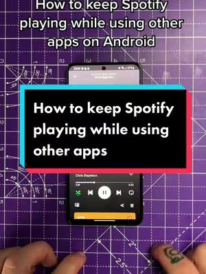 The cover image shows a setup with two smartphones on a purple surface marked with gridlines, potentially a cutting mat. The top phone displays a screen with text, while the bottom phone showcases the Spotify app's interface. A text overlay in a black box with blue and red outlines provides instructions. Two hands, one with a tattoo, are visible at the bottom.