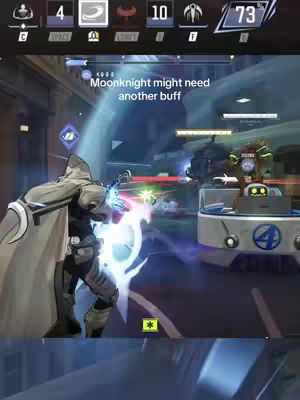 A screenshot from a video game featuring the Marvel character Moonknight. The image is a wide shot showing in-game action, with Moonknight in the foreground, positioned on the left side. The background is a futuristic cityscape setting. The character is rendered in a dynamic pose, surrounded by blue energy effects, suggesting an active ability or attack. The upper part of the screen displays the game's heads-up display (HUD), which includes health bars and other game elements. A text overlay at the top reads "Moonknight might need another buff".