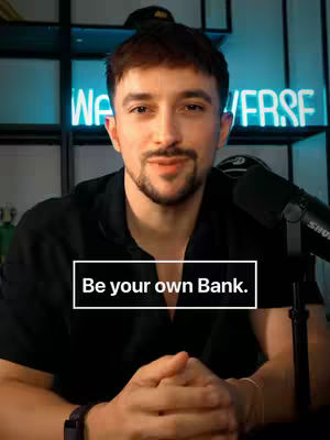 A well-lit, indoor shot featuring a man in a black shirt. The background includes a neon sign that reads "WE VERSE". The man is positioned centrally, looking towards the camera, with a framed text that says "Be your own Bank."