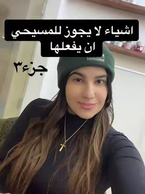A selfie-style shot featuring a woman wearing a green beanie and a black top, framed from the chest up. The background is slightly blurred but suggests an interior setting. Text overlays are placed at the top and bottom. She is looking directly at the camera and has a necklace with a cross. The overall setting is casual, with good lighting.