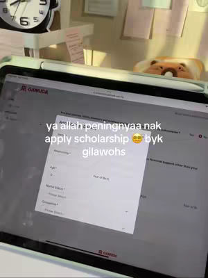 A person is working on a tablet, the screen displays a web page, an overlay asking questions about applying for a scholarship. In the background, there is a clock, some papers and a stuffed animal. The color palette is muted with lights from above.