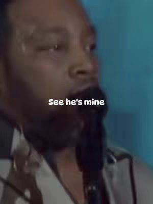 The image shows a close-up of a man's face from the chest up. He is wearing a white shirt. Overlay text states, "See he's mine". The background has a blue tone.