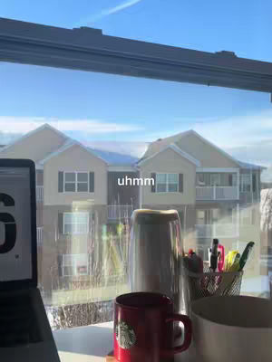 The cover image shows an interior scene with a window overlooking an apartment complex and a blue sky. In front of the window sit items like a laptop with its screen partially visible. On the windowsill or desk are a red Starbucks mug and other desk or study desk supplies, the text of the image hook is on the window.