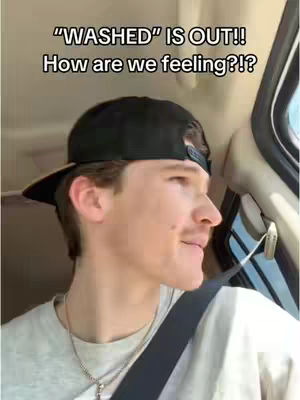 A man in a car wearing a backward black cap and a gray t-shirt looks to the side, with text overlayed at the top. The car interior is visible in the background.