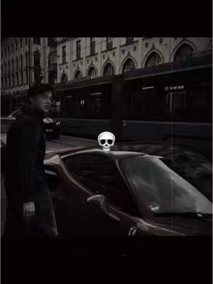 The cover image presents a grayscale scene. A man in a black coat and hat stands next to what appears to be a red sports car. A white skull graphic is superimposed on the car, suggesting a theme of danger or perhaps the transient nature of wealth. The background features a street scene with buildings and a tram.