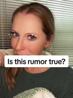 A woman with fair skin and light brown hair is centered in the frame. She's wearing a dark green shirt and has a white rectangle overlaid with the text, 'Is this rumor true?' The background is composed of horizontal blinds.