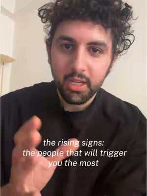 A man with curly dark hair and a beard is shown in a close-up shot. He is wearing a black shirt and is gesturing with his right hand. Text overlays appear on the image, indicating the content.
