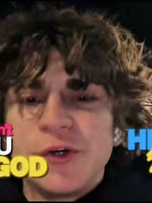 A close-up shot of a young man with curly brown hair. He is looking at the camera and speaking. Text overlays are added to the image in different colors and fonts.