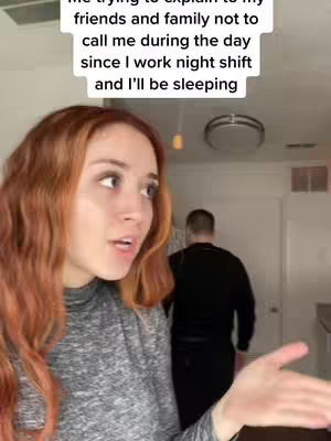 The cover image features a woman with red hair, looking towards the left side of the frame. The background is a room, with a man walking in the background to the right. Text overlayed on top of the image reads, 'me trying to explain... night shift and I'll be sleeping'.