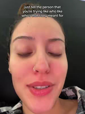 A close-up shot of a woman's face taken from a slightly low angle. She has dark hair pulled back, a nose ring, and is wearing a checkered shirt. The background is dark. Text in a white sans-serif font overlays the top of the image.