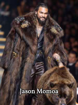 The image showcases Jason Momoa on a runway. He is wearing a long, dark brown fur coat, leather pants, and a black shirt. A bear is in front of him. The background is blurred, implying a fashion show setting.
